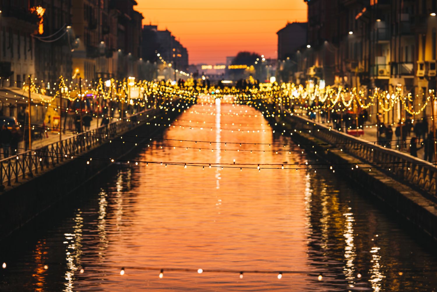 Sunset view of a canal with lights reflecting on the water — romantic cityscape in golden hour.