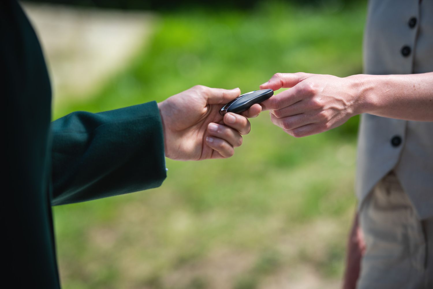 Close-up of hands exchanging car keys — symbolic gesture of trust or transfer.
