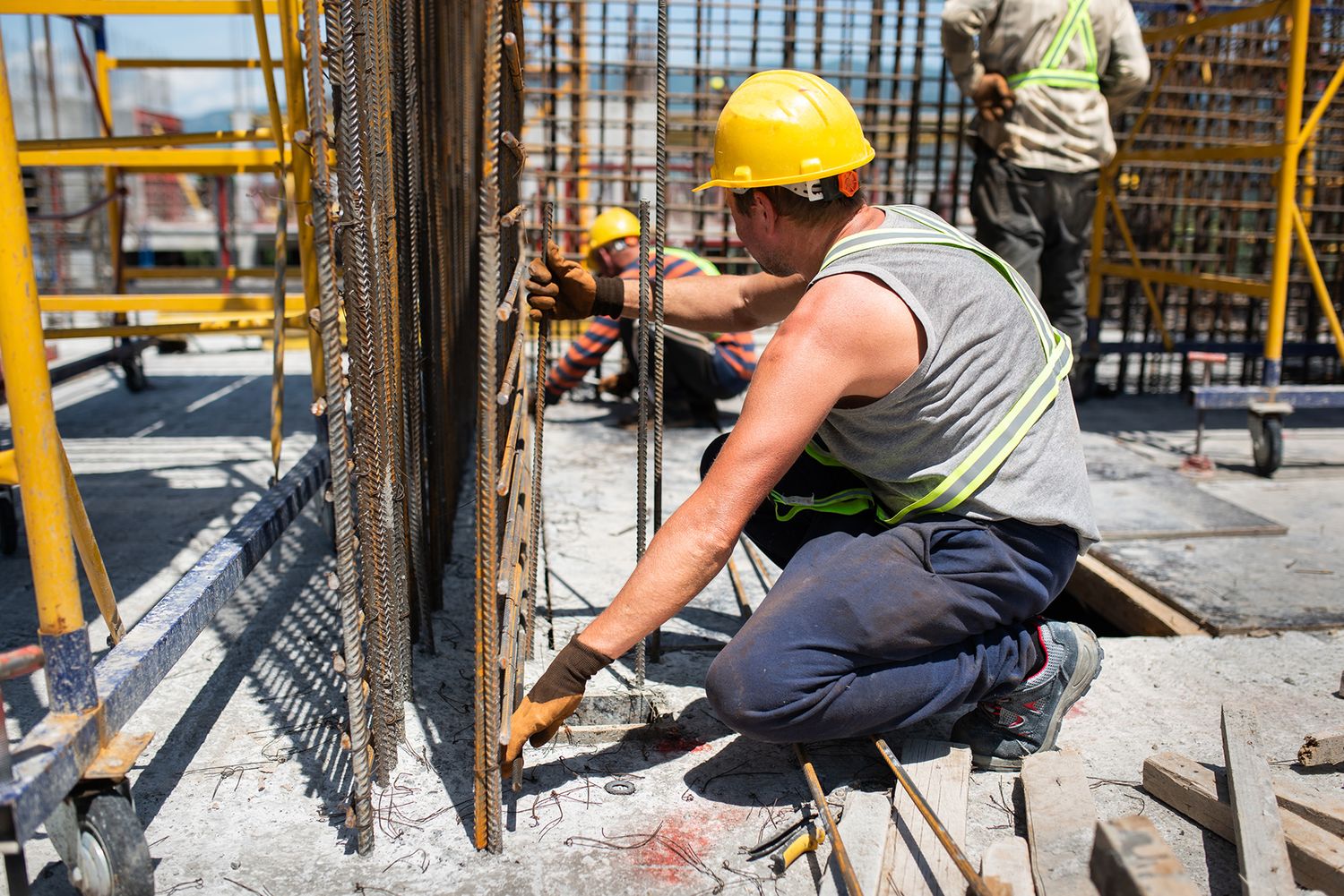 Worker assembling rebar for a structural column on a commercial construction site.