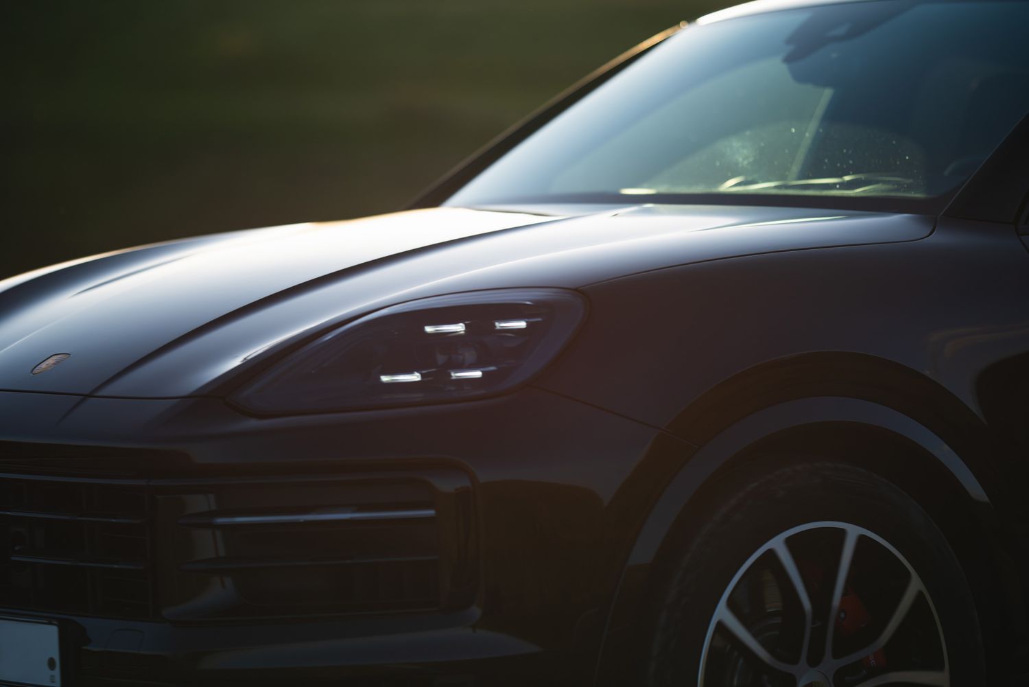 Close-up of a dark red luxury SUV — dramatic shadow and design detail.
