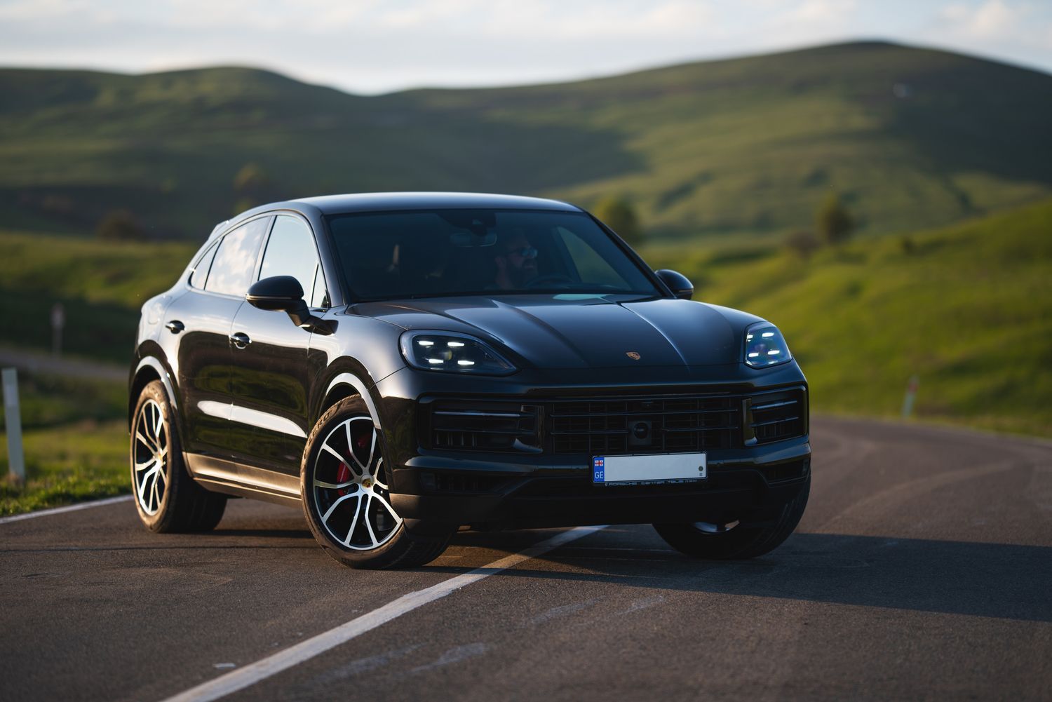 Black SUV driving on winding mountain road — dynamic automotive shot in nature.