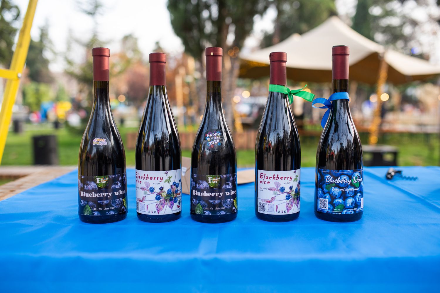 Outdoor display of Georgian wine bottles on a blue table during a local festival.