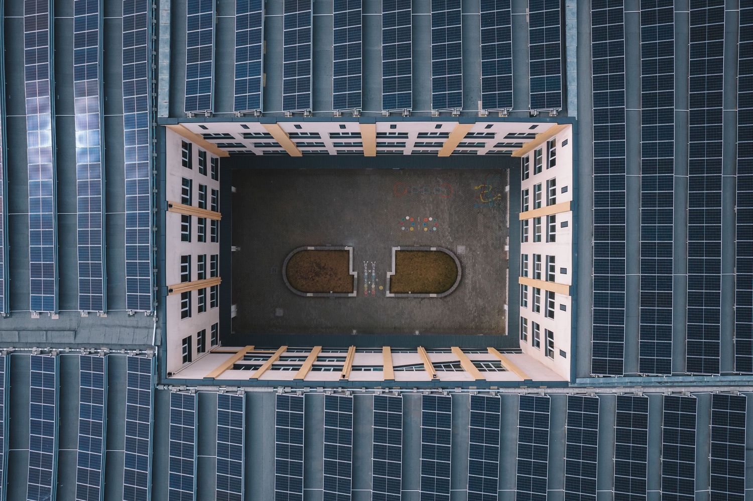 Top-down aerial view of a rooftop swimming pool surrounded by tall buildings — urban geometry.