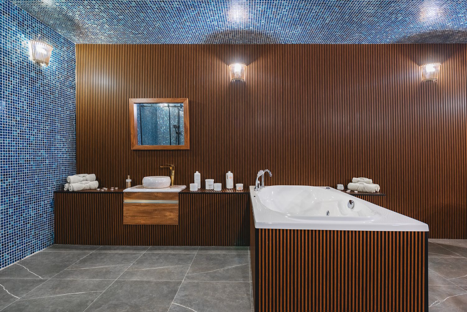 Private spa suite with mosaic-tiled walls and a treatment bed, ideal for massage or body therapy services.