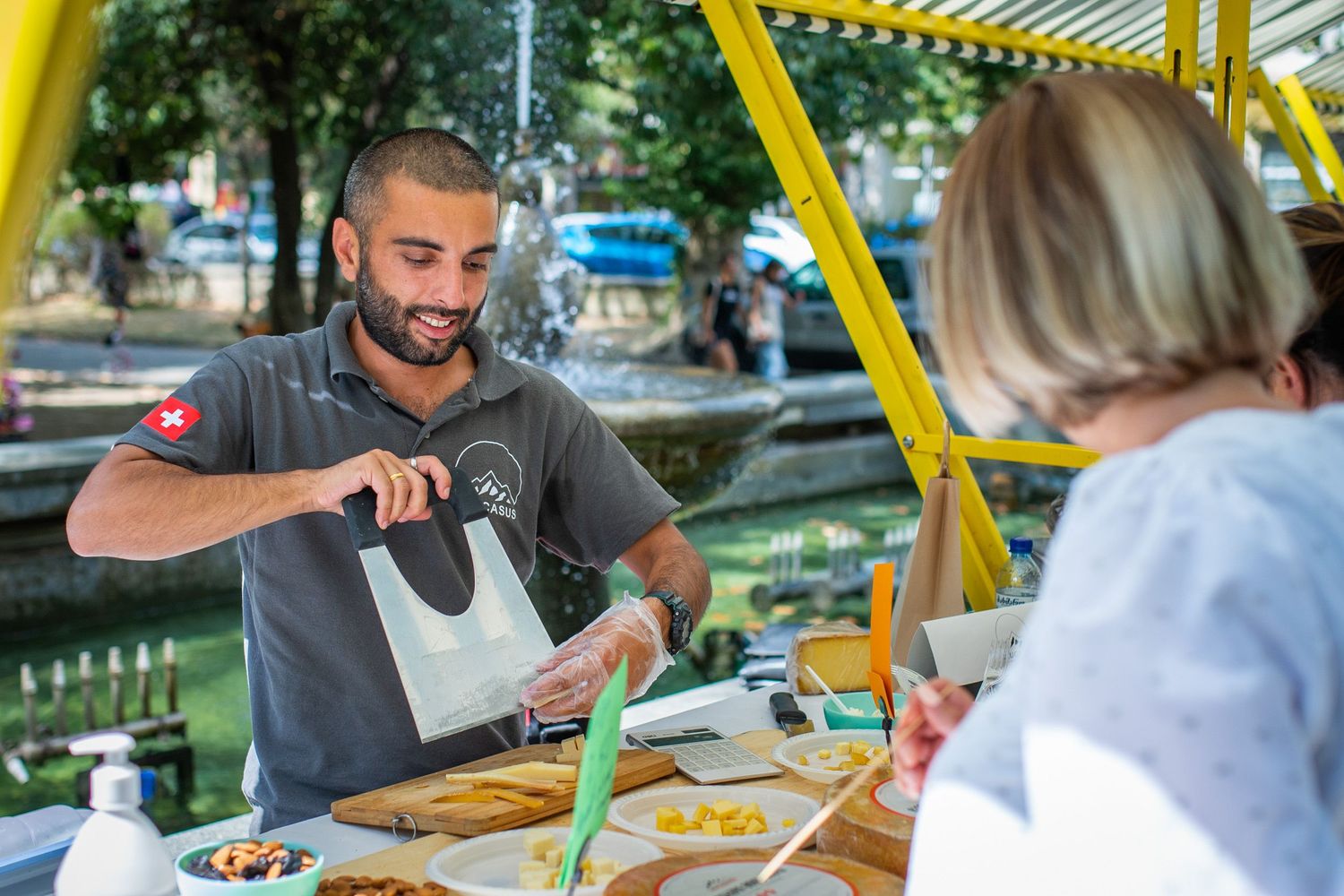 Man serving fresh juice or smoothie at an open-air health food fair.