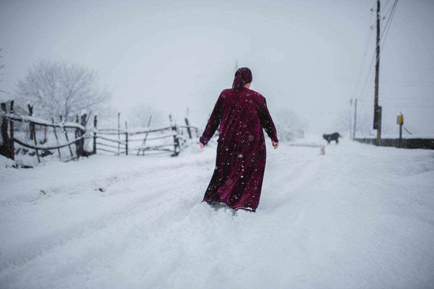 Solitary figure in religious robes walking through deep snow on a cold winter day.