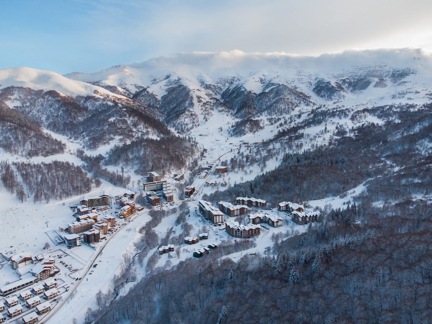 Mountain valley with winding roads and snow-covered peaks in remote Georgia.