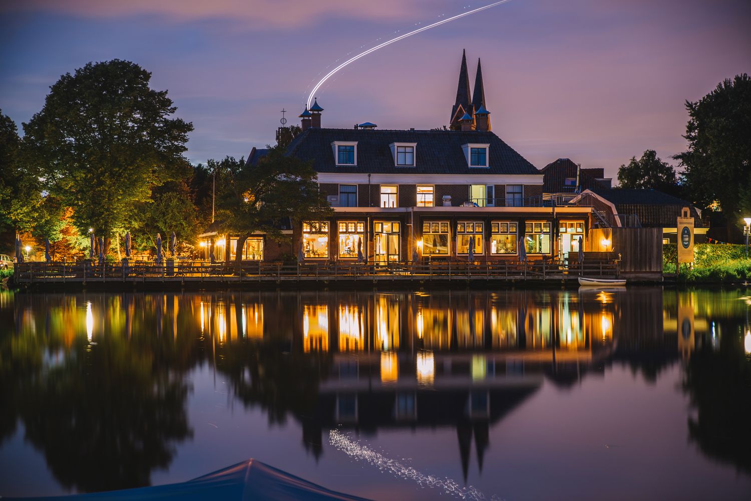 Elegant riverside building reflected on calm water at sunset — romantic evening view.