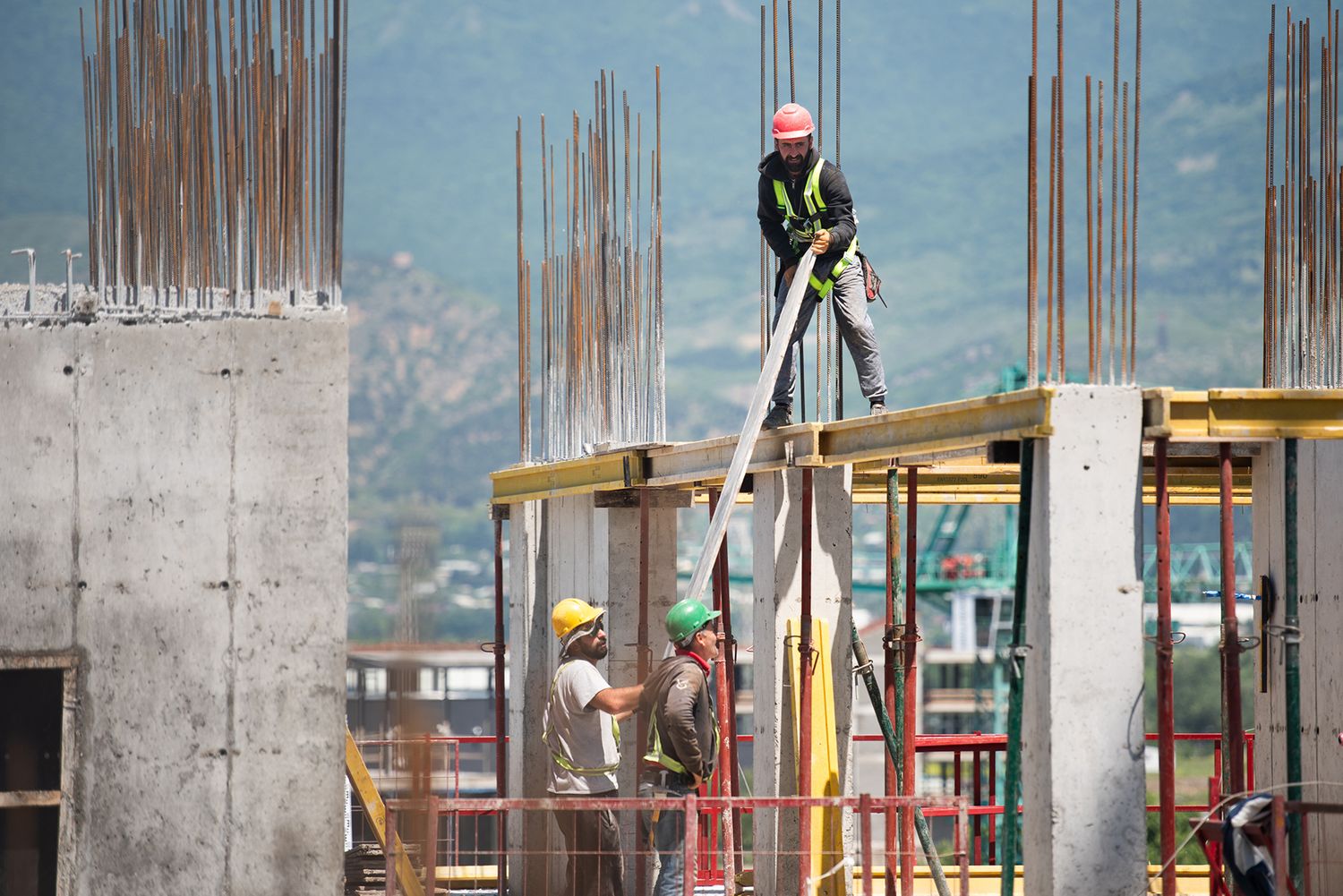 High-altitude worker balancing on structural beams at a multistory building site.