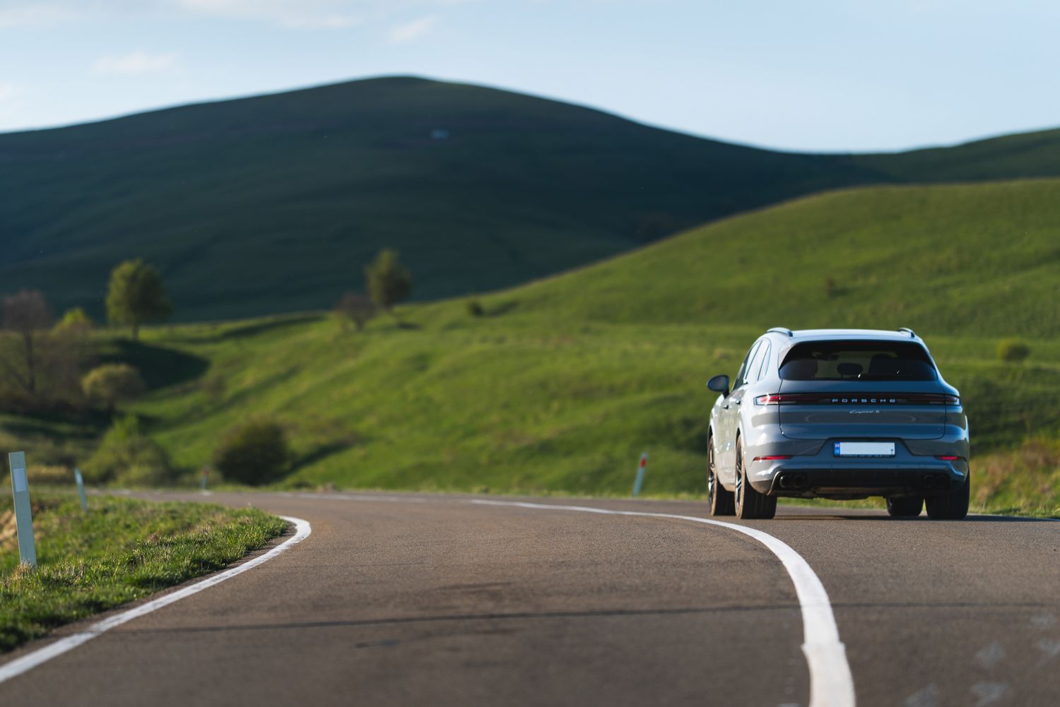 Front-facing shot of a white vehicle approaching on a winding countryside road.