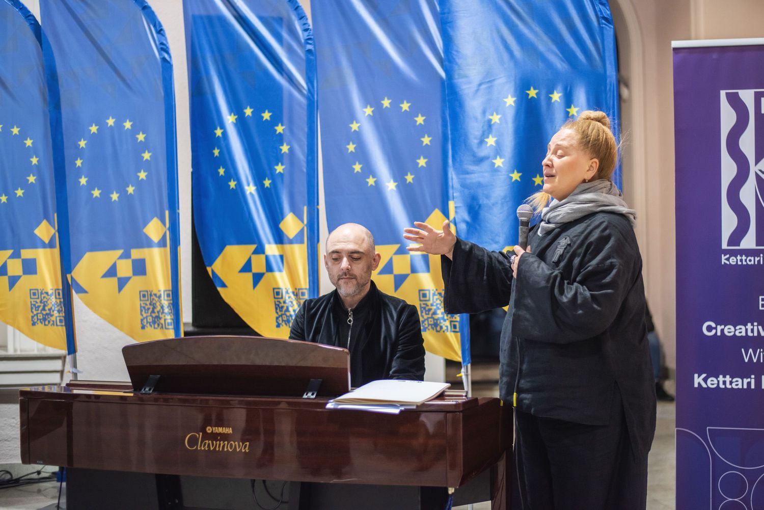 A formal speaker addressing an audience on stage in front of EU and Georgian flags.