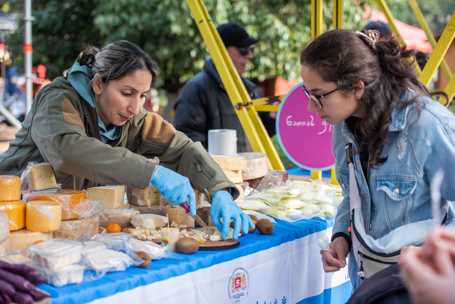 Young women decorating cookies or pastries at a baking station in a food festival.