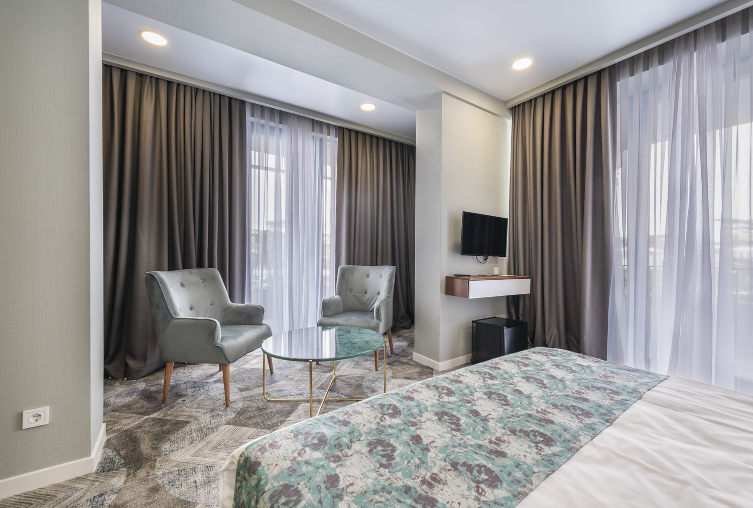 Modern hotel room with twin beds, neutral tones, and a large window with blackout curtains, offering a cozy and elegant stay.