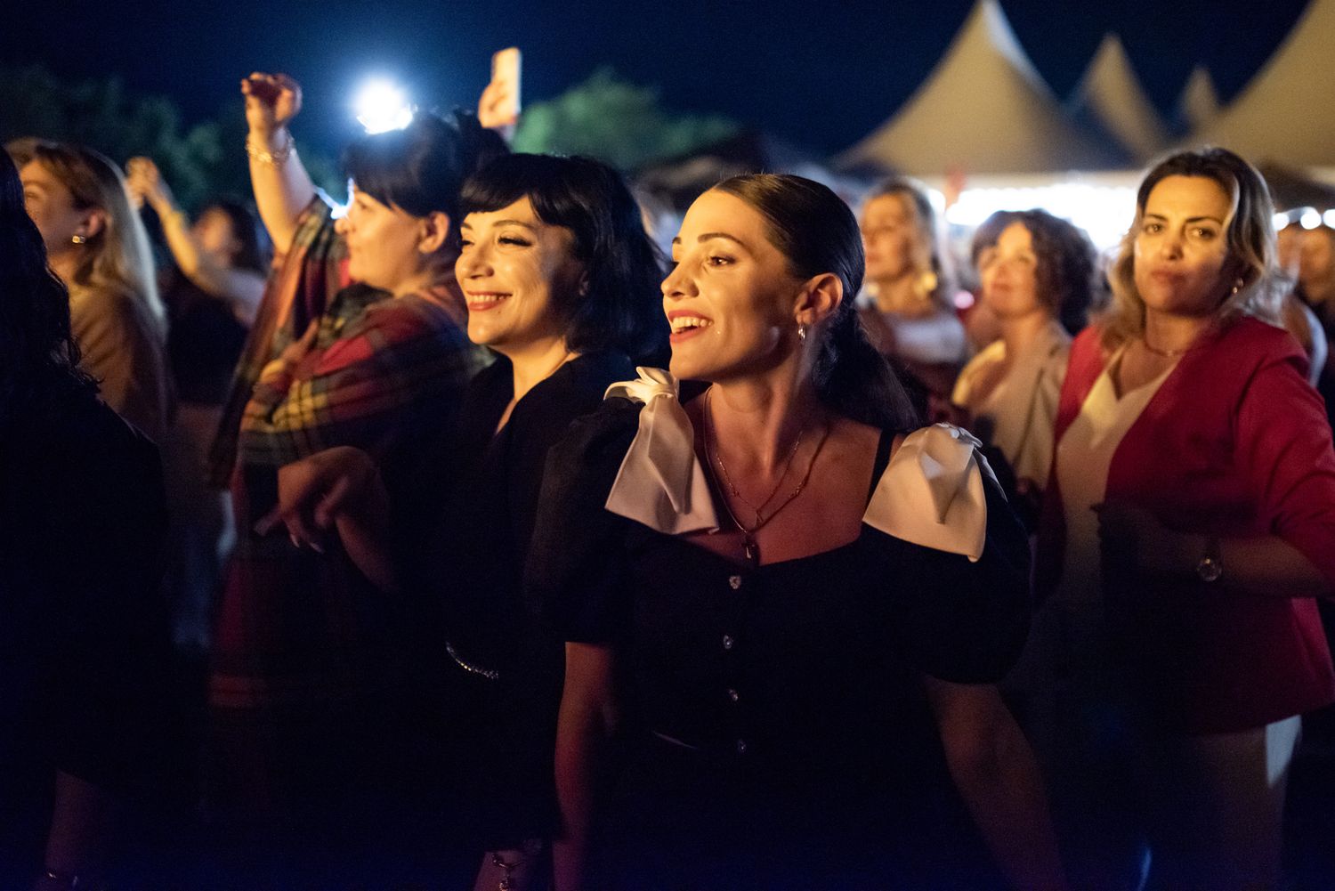 Excited crowd watching a performance at a nighttime outdoor festival.