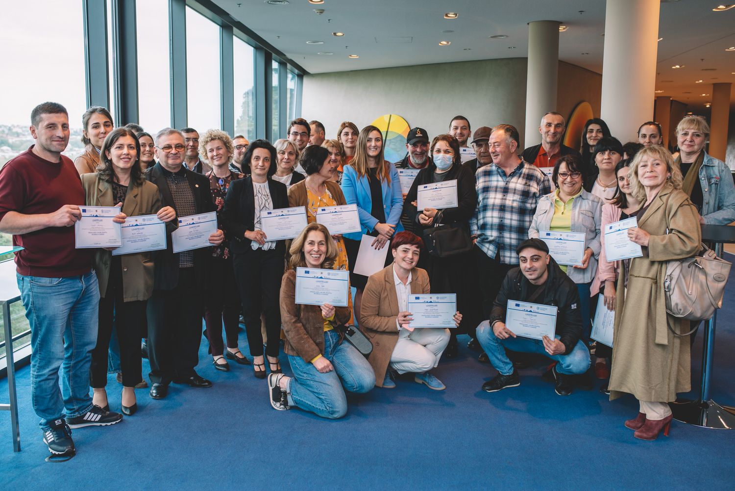 Large group of students and young adults posing in a modern conference room.