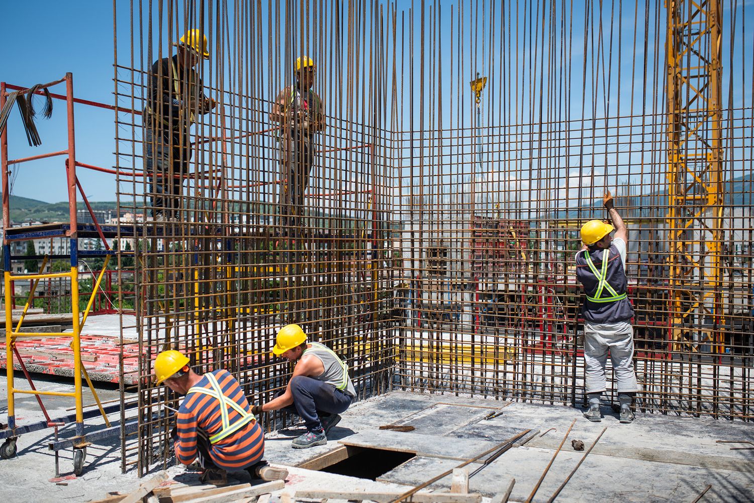 Multiple workers operating within a reinforced concrete zone, setting up mesh and supports.