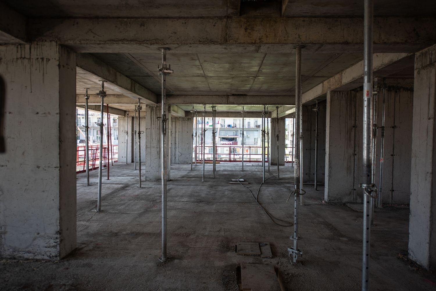 Empty interior of an unfinished building floor with exposed concrete and open window frames.