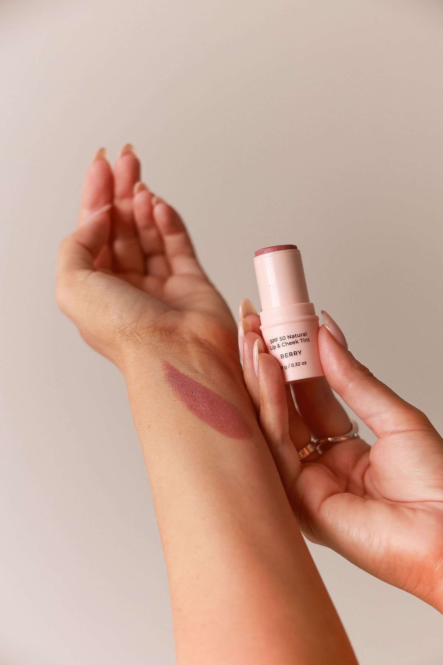 Hands holding and applying skincare product on skin.