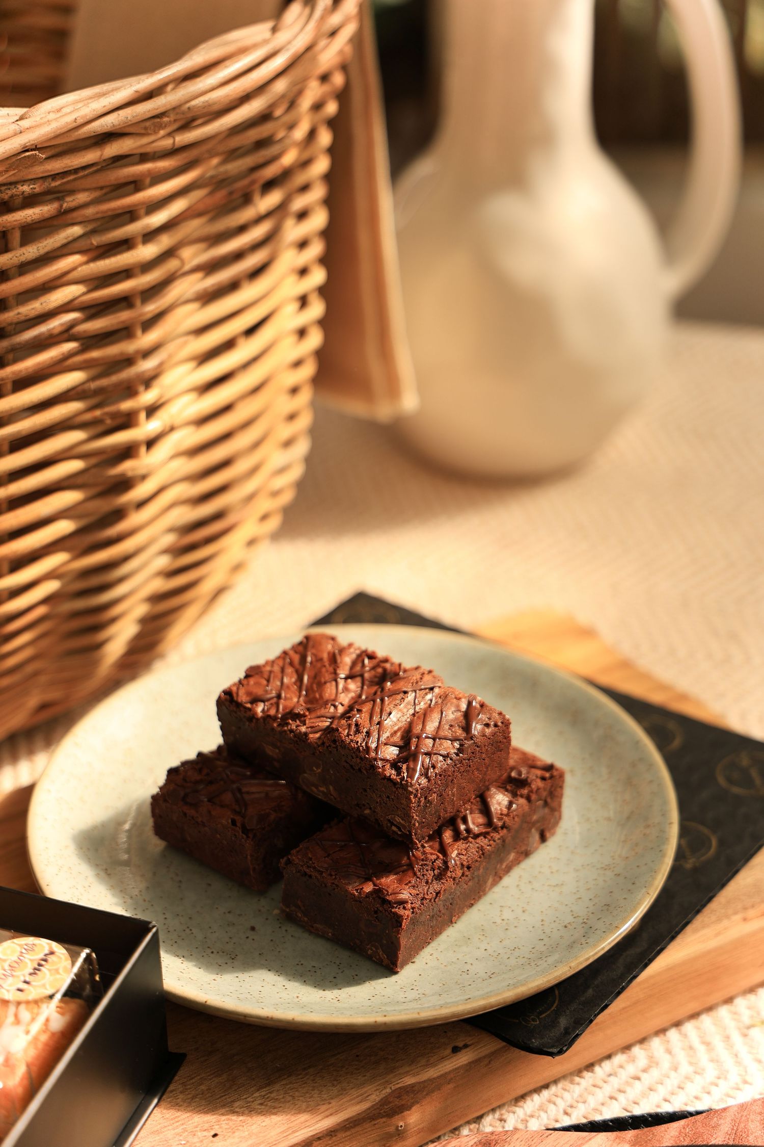 Chocolate brownies served on grey plate with wicker basket in background.