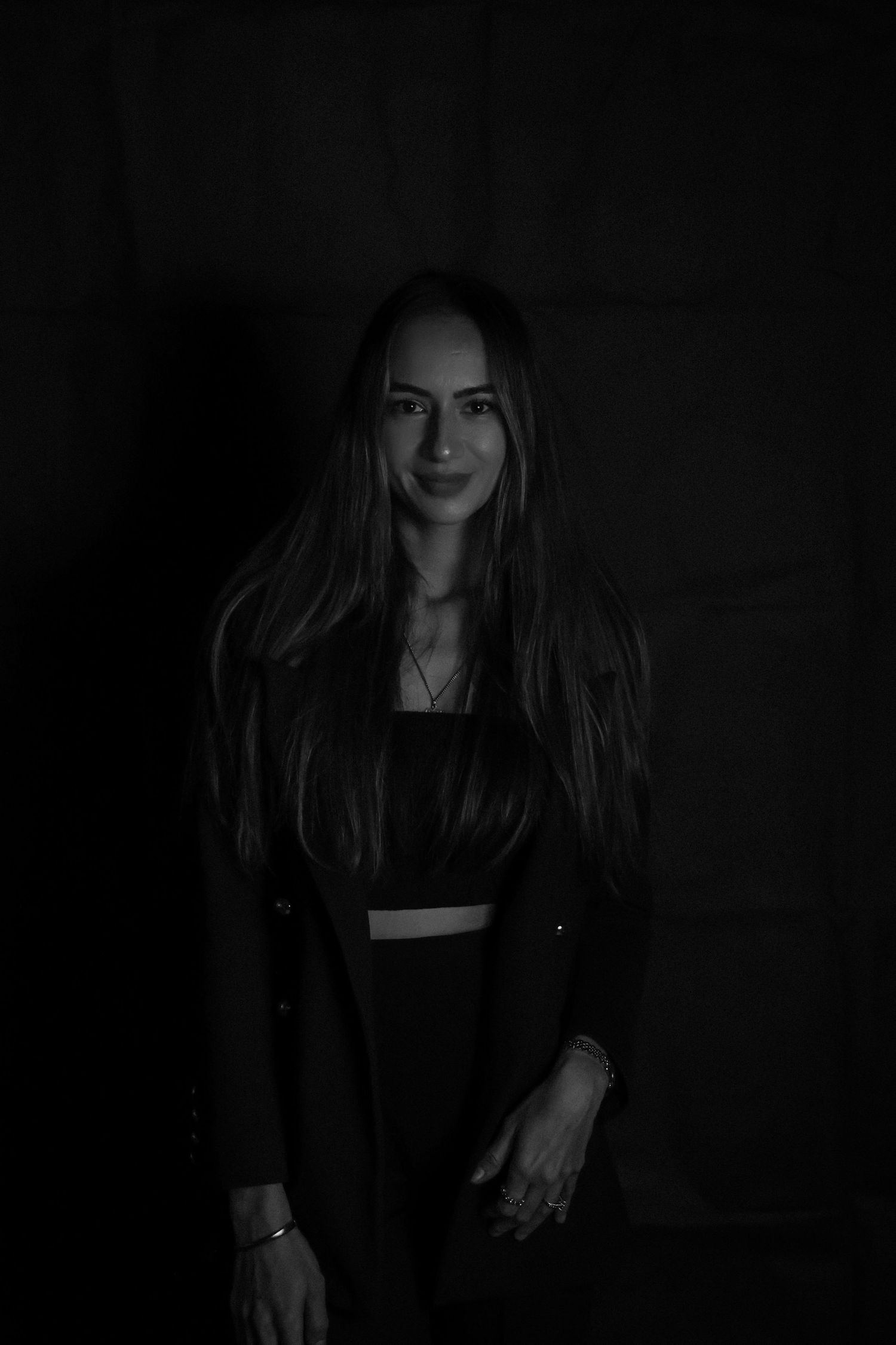 Black and white portrait of woman in dark clothing against minimalist background.