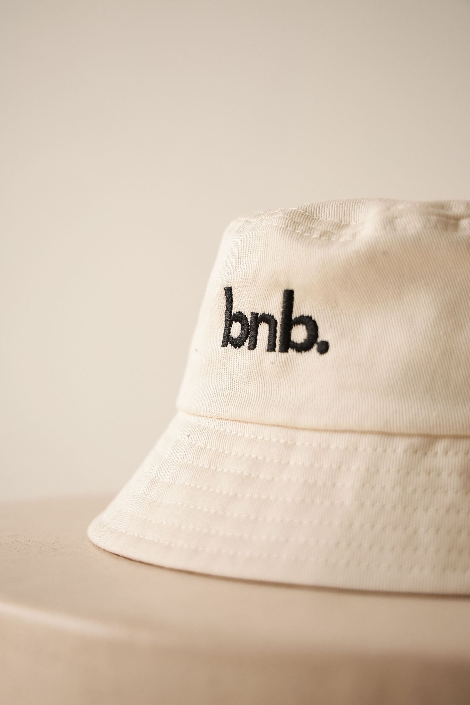 Cream colored bucket hat with 'bnb' embroidered text on a neutral background.