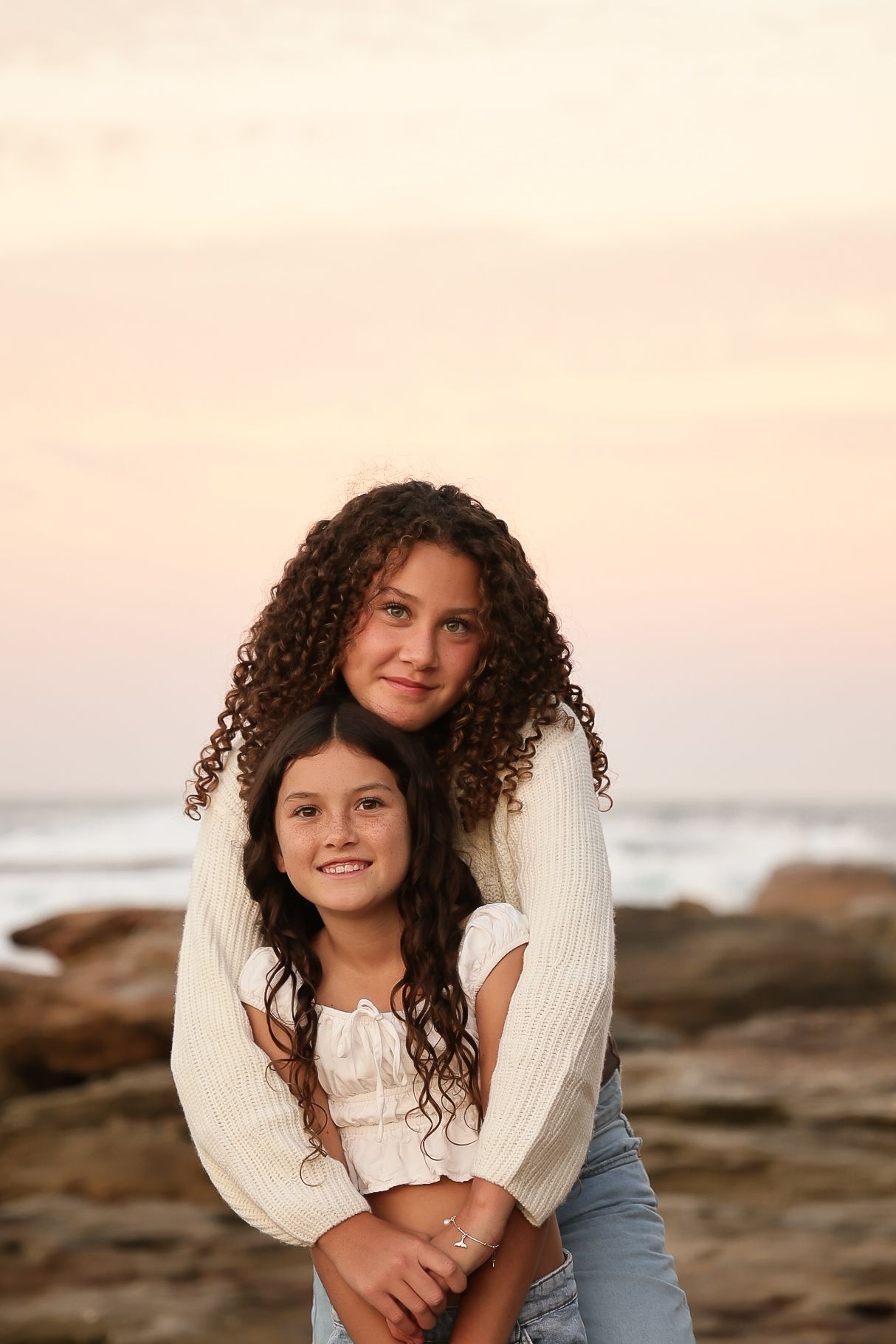 Candid portrait on rocky beach during sunset with natural curly hair.