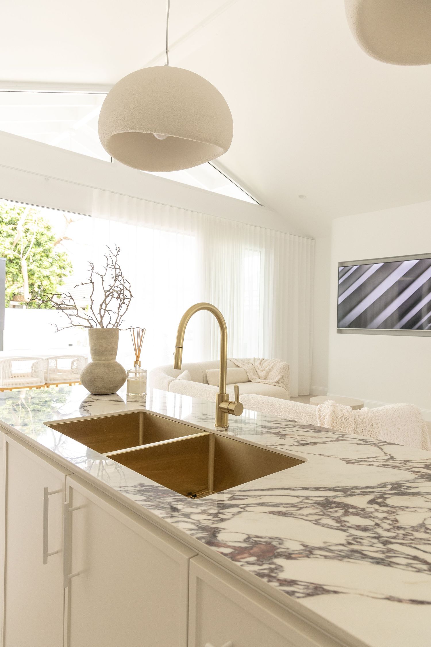 Luxurious kitchen featuring marble countertops, gold faucet, and dome pendant light.