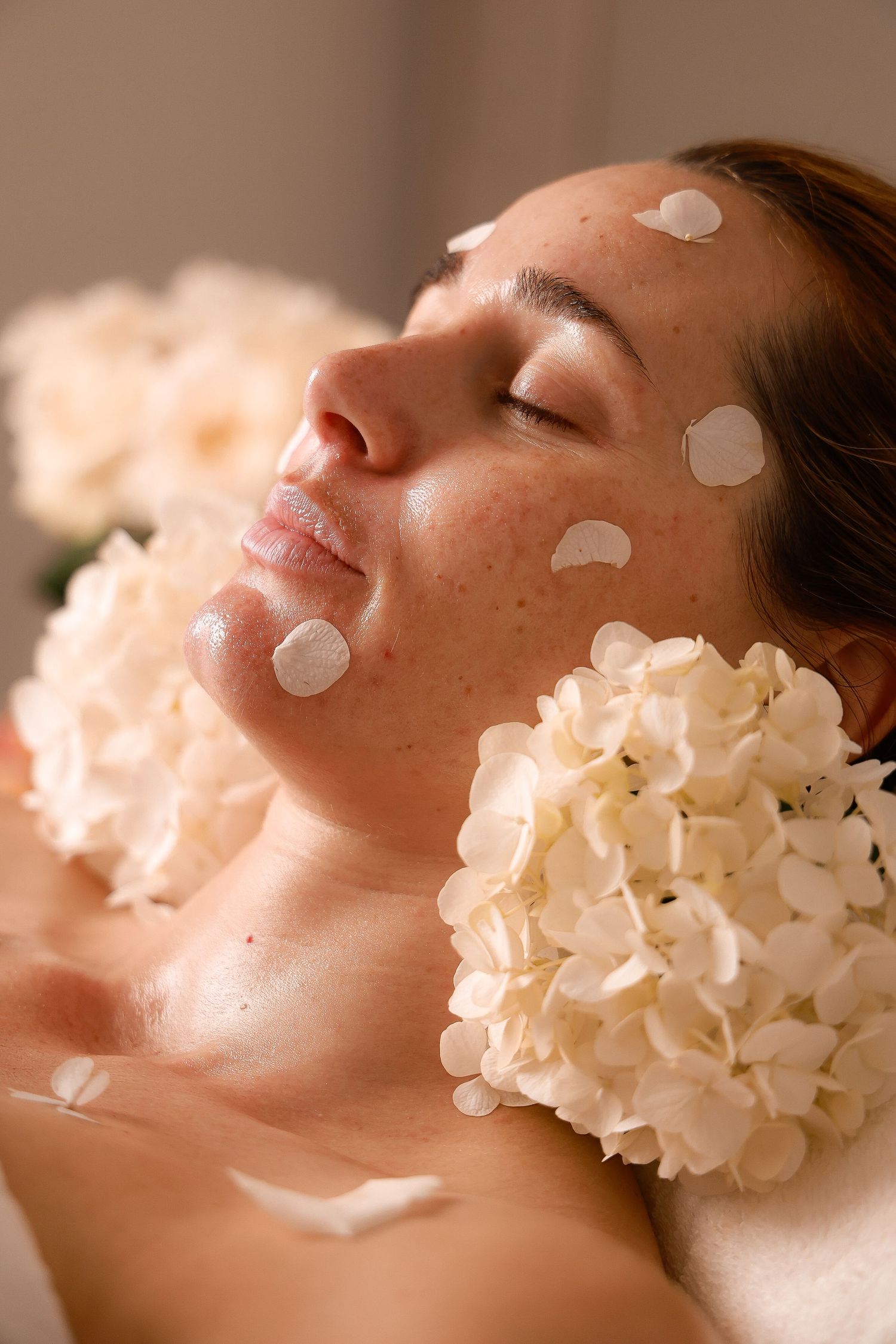 Spa treatment photo with white hydrangea flowers and facial cream dots in soft lighting.