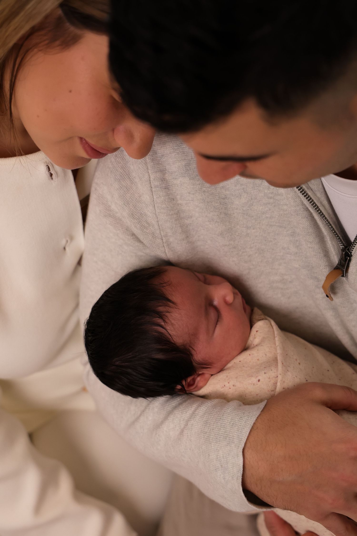 Tender moments captured between parent and newborn in soft lighting.