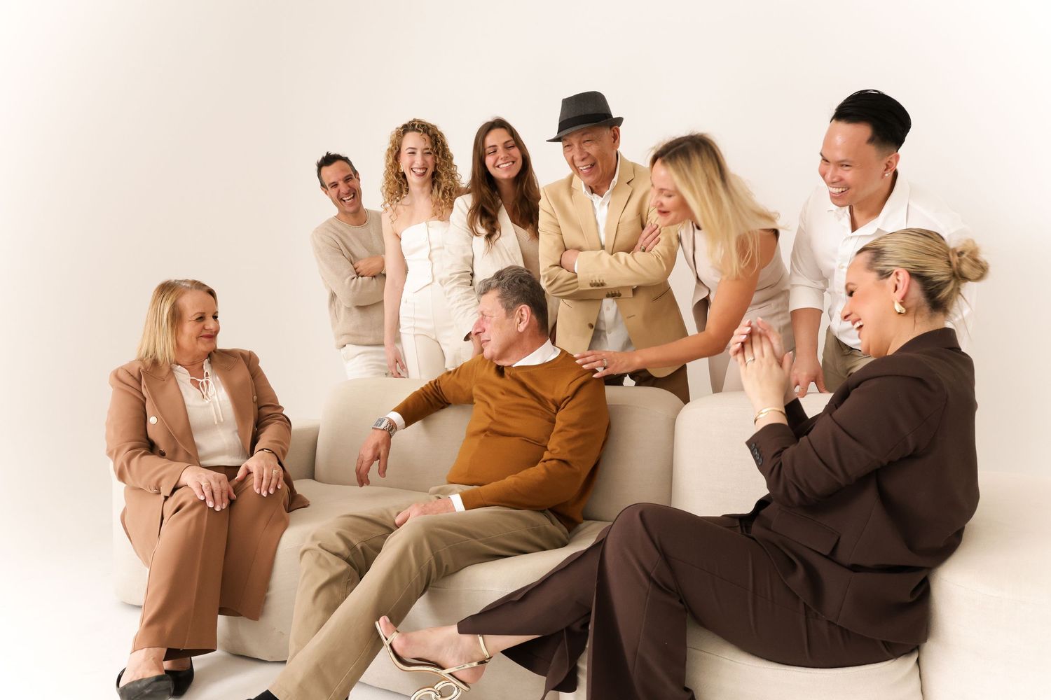 People lounging on furniture in cream and brown tones during a casual photoshoot.