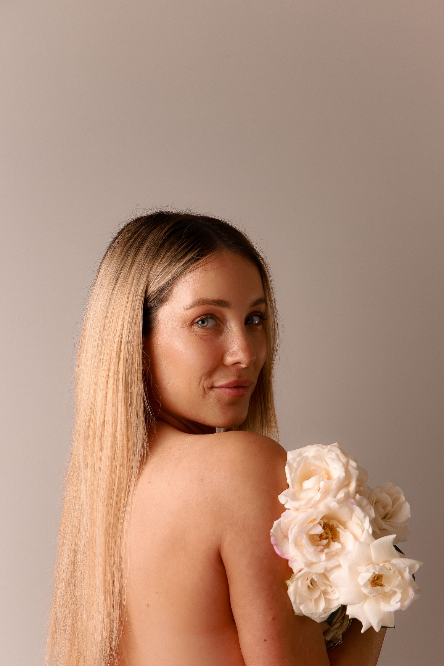 Artistic portrait with delicate white flowers against neutral backdrop.