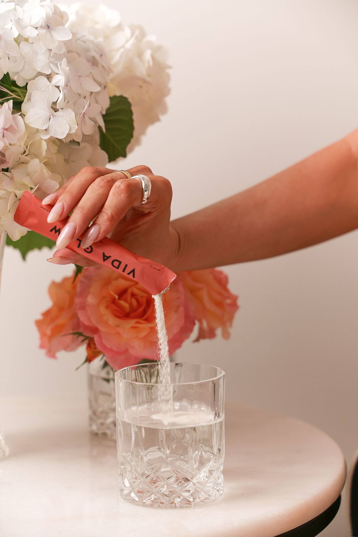 Arranging flowers in crystal vase with beauty products nearby.