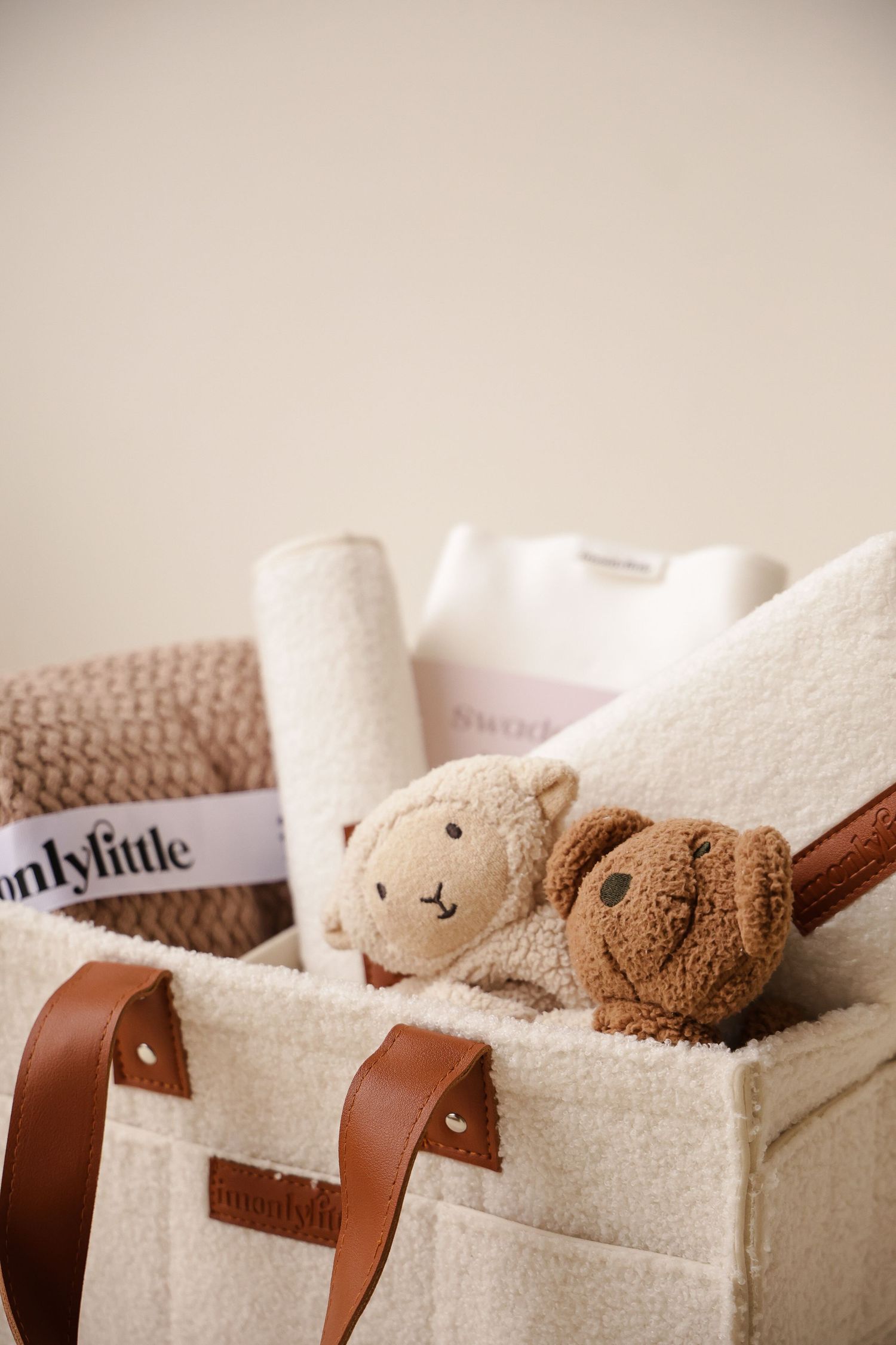 Close-up of soft teddy bears nestled in cream-colored storage tote with leather straps.