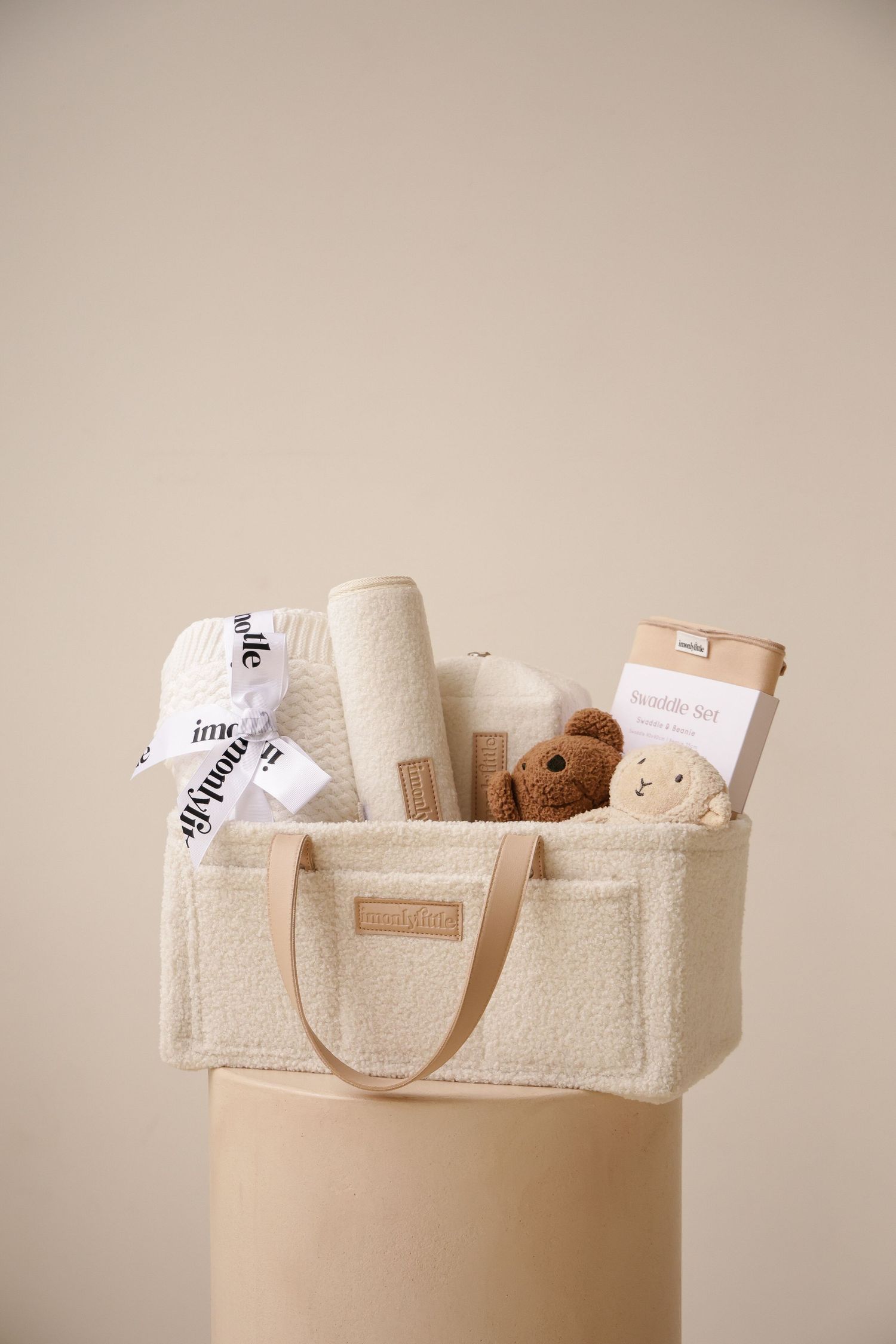 Organized baby items and soft toys displayed in cream-colored tote bag.