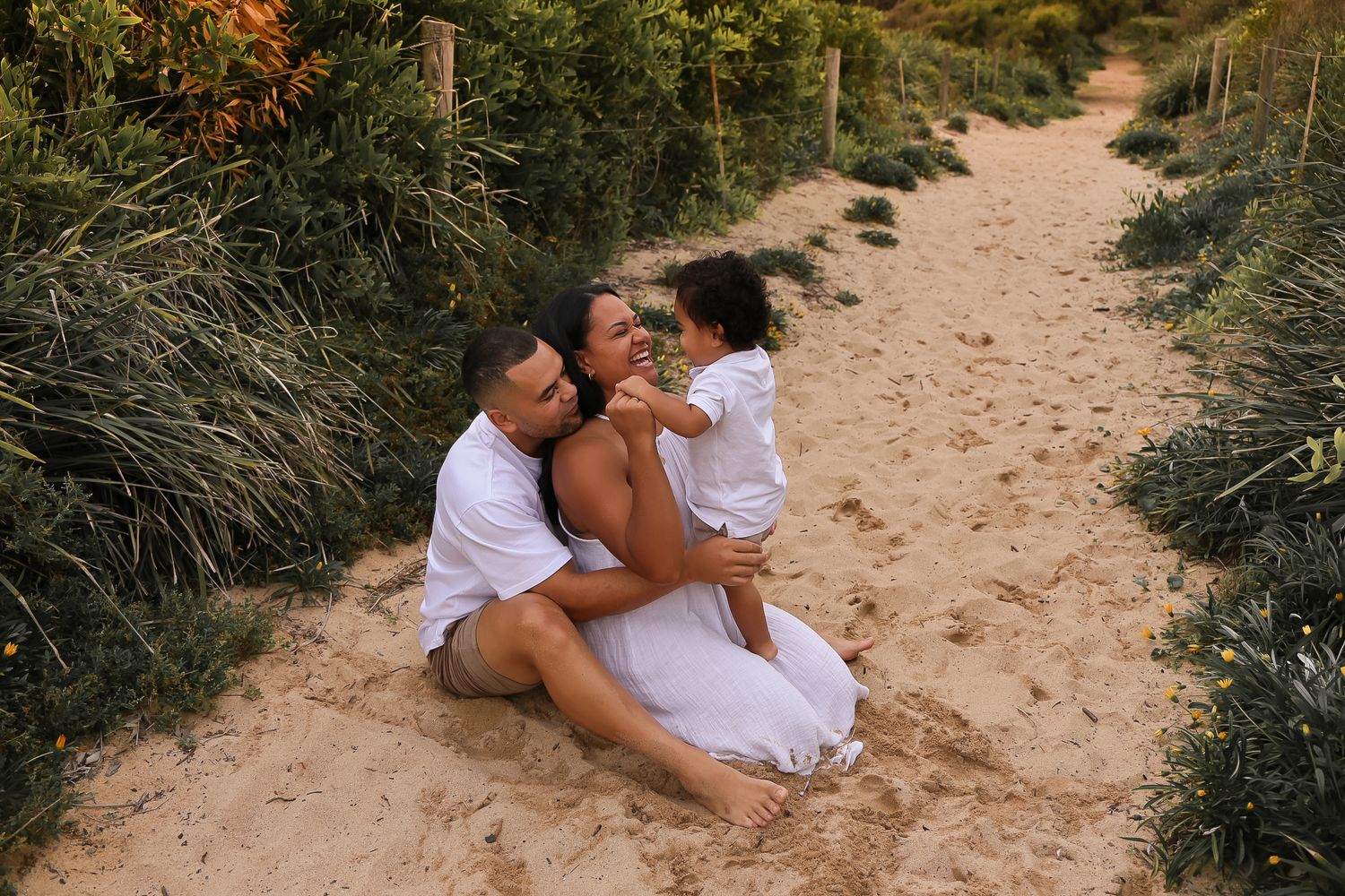 Intimate couple shares romantic moments on a sandy beach path during sunset.