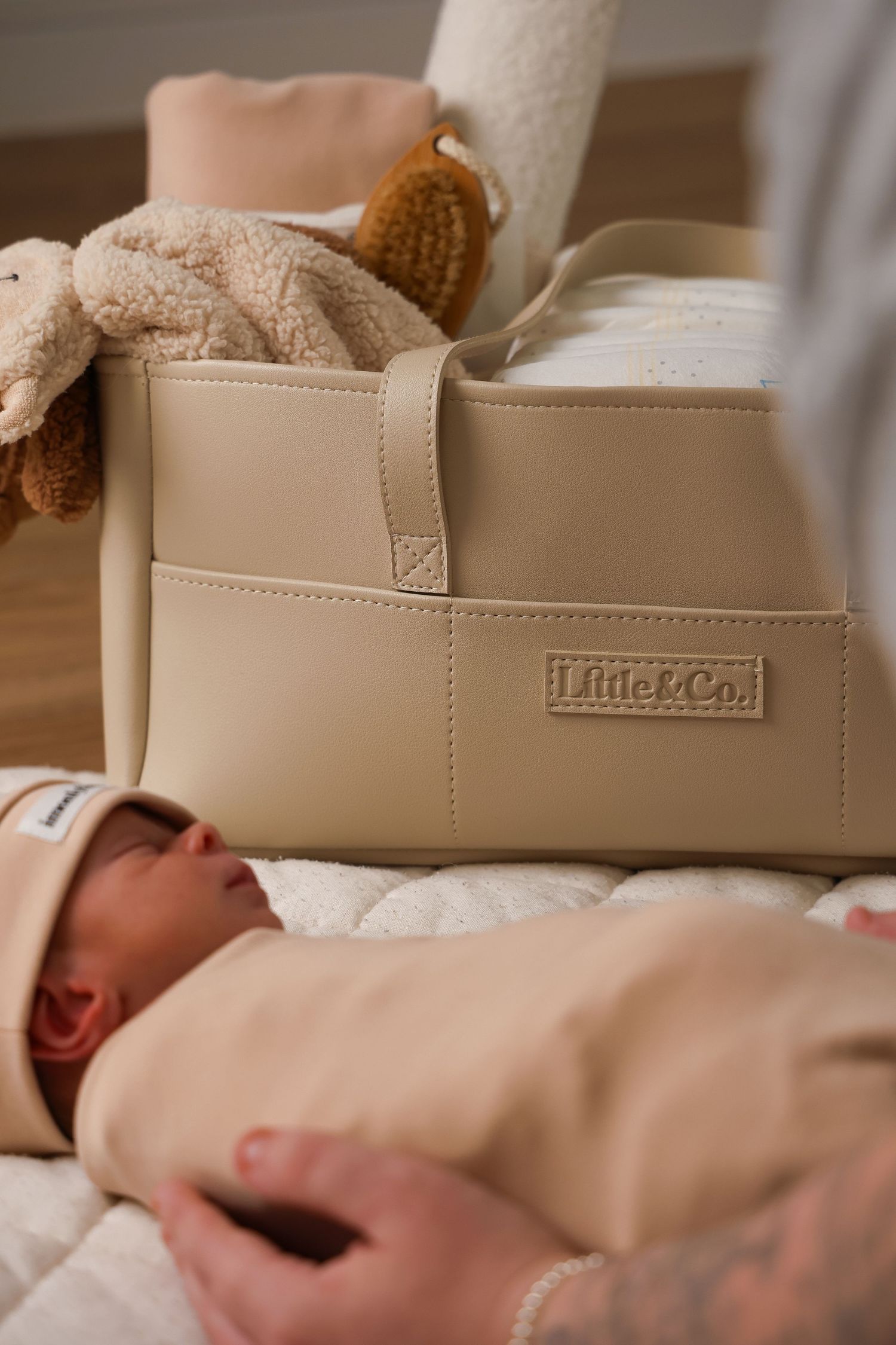 A beige Little Moon branded baby shoe displayed on soft white fabric.