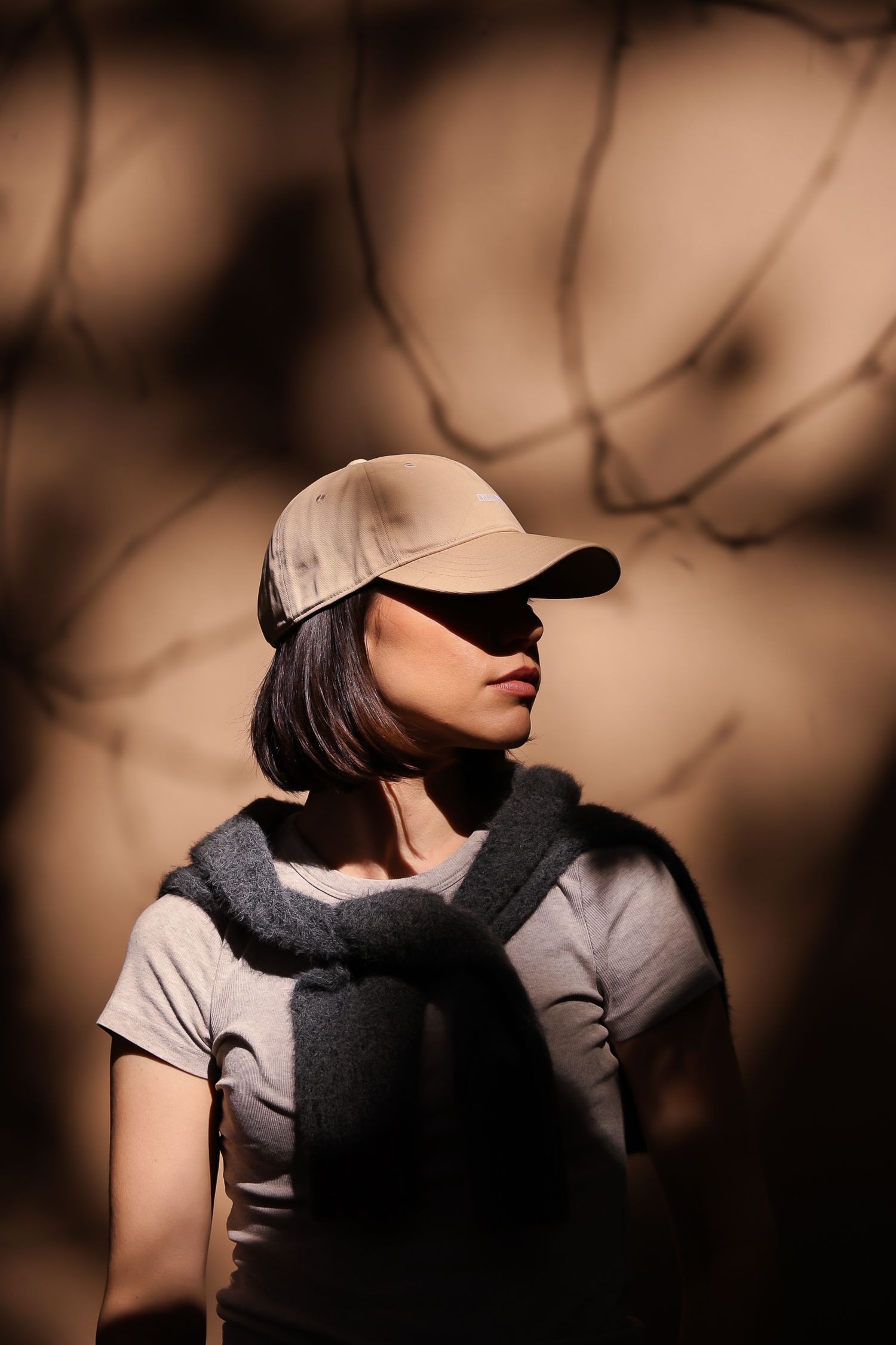 Artistic portrait of person in baseball cap and backpack with dramatic shadow effects.