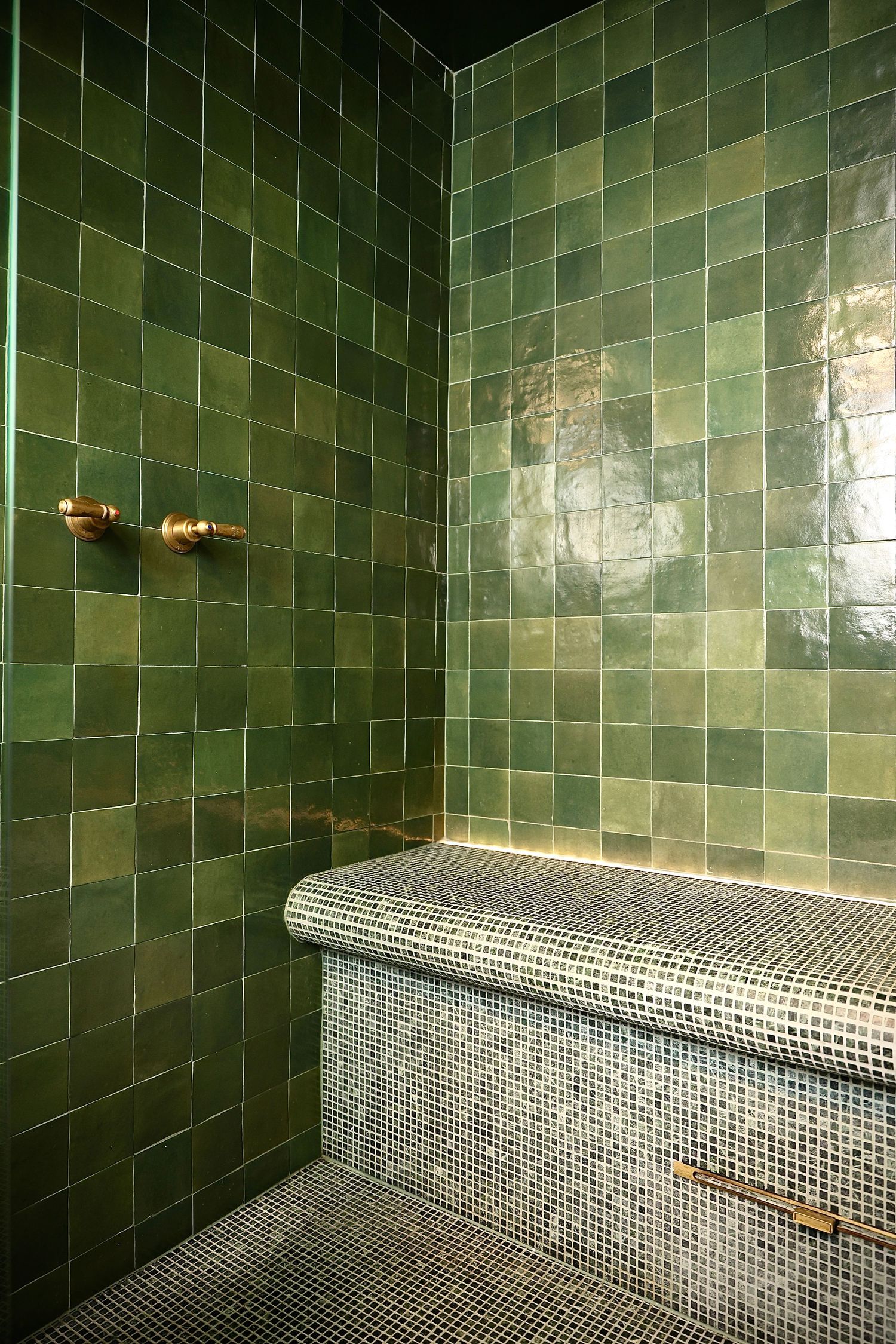 Spa-like space with emerald green tile walls and mosaic-tiled curved bench seating.