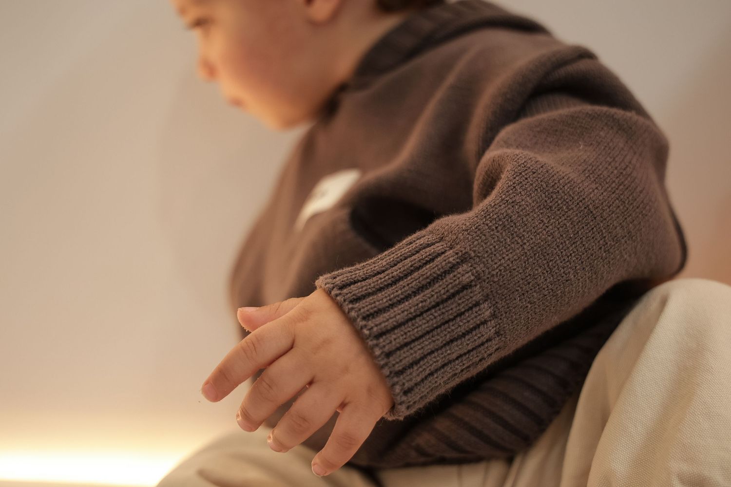 Close-up detail of brown knit hoodie texture on child's clothing.