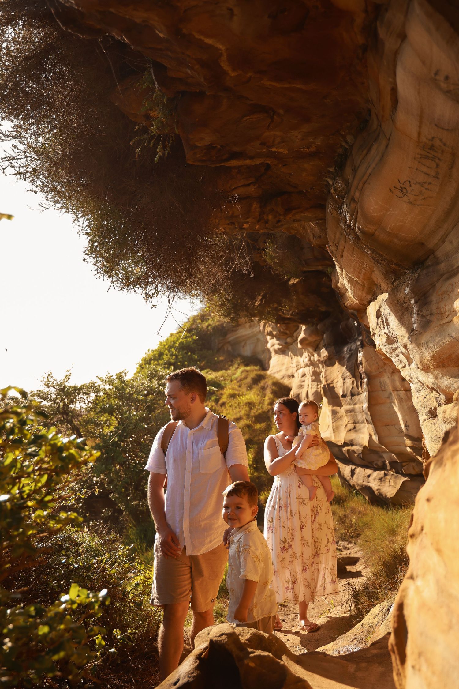 Family exploring a scenic cave pathway with golden sunlight filtering through the natural rock formations.