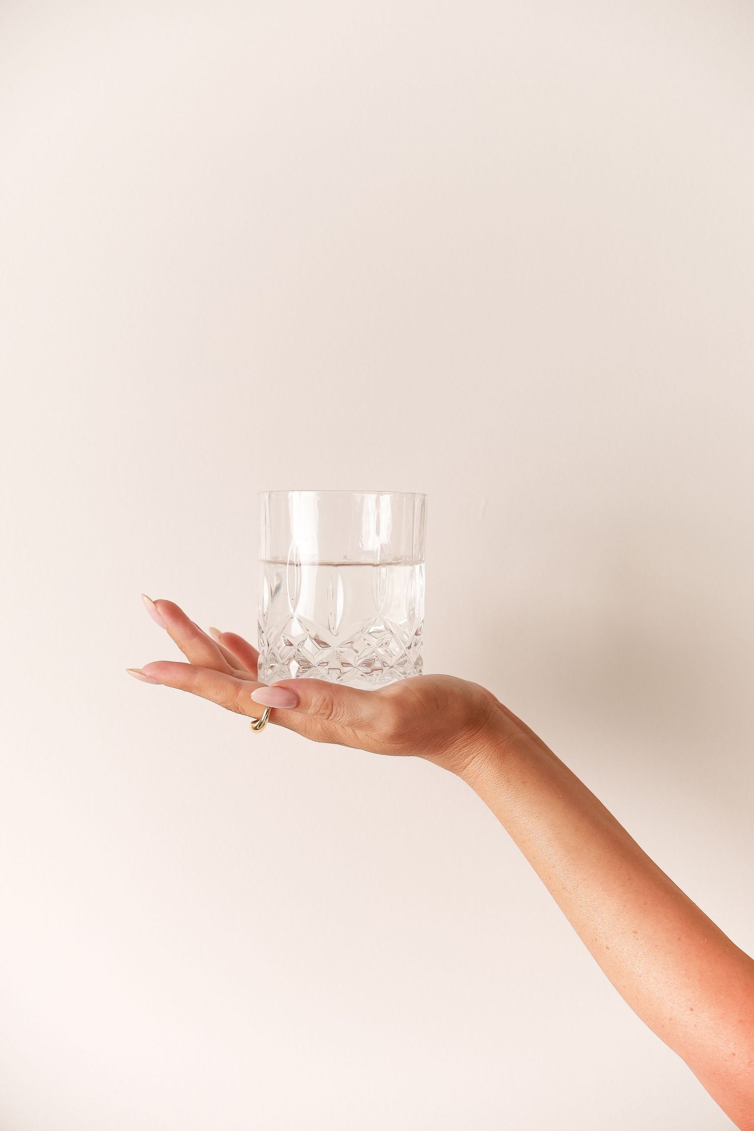 Crystal glass being balanced on fingertips against white background.