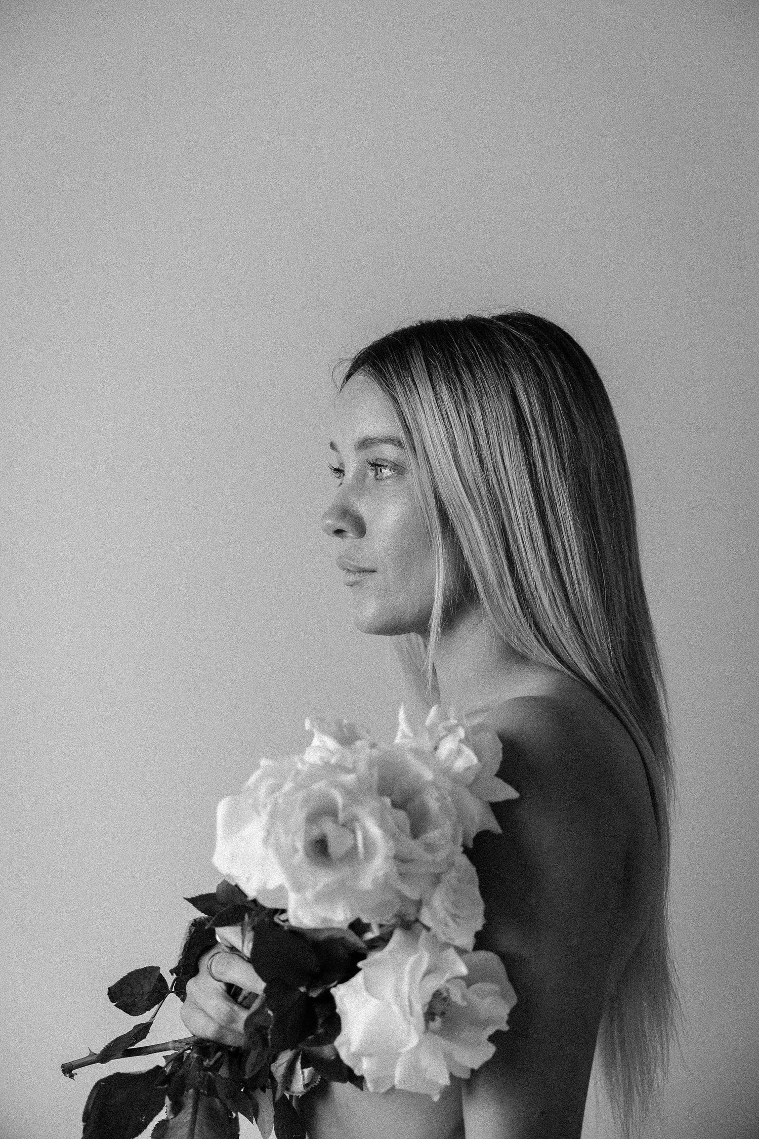 Black and white artistic portrait with white roses in profile view.