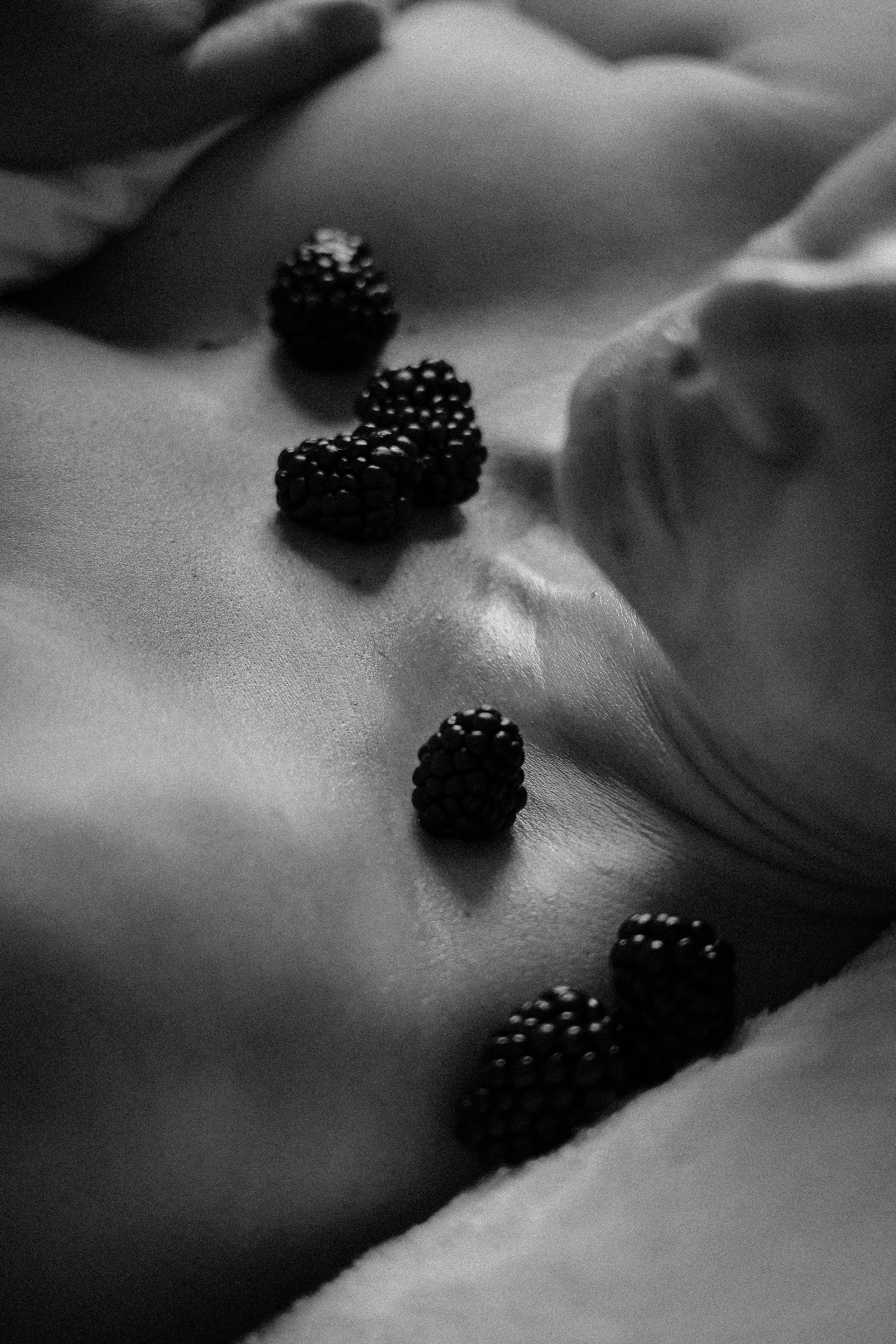 Black and white photo featuring blackberries artistically placed in a beauty setting.