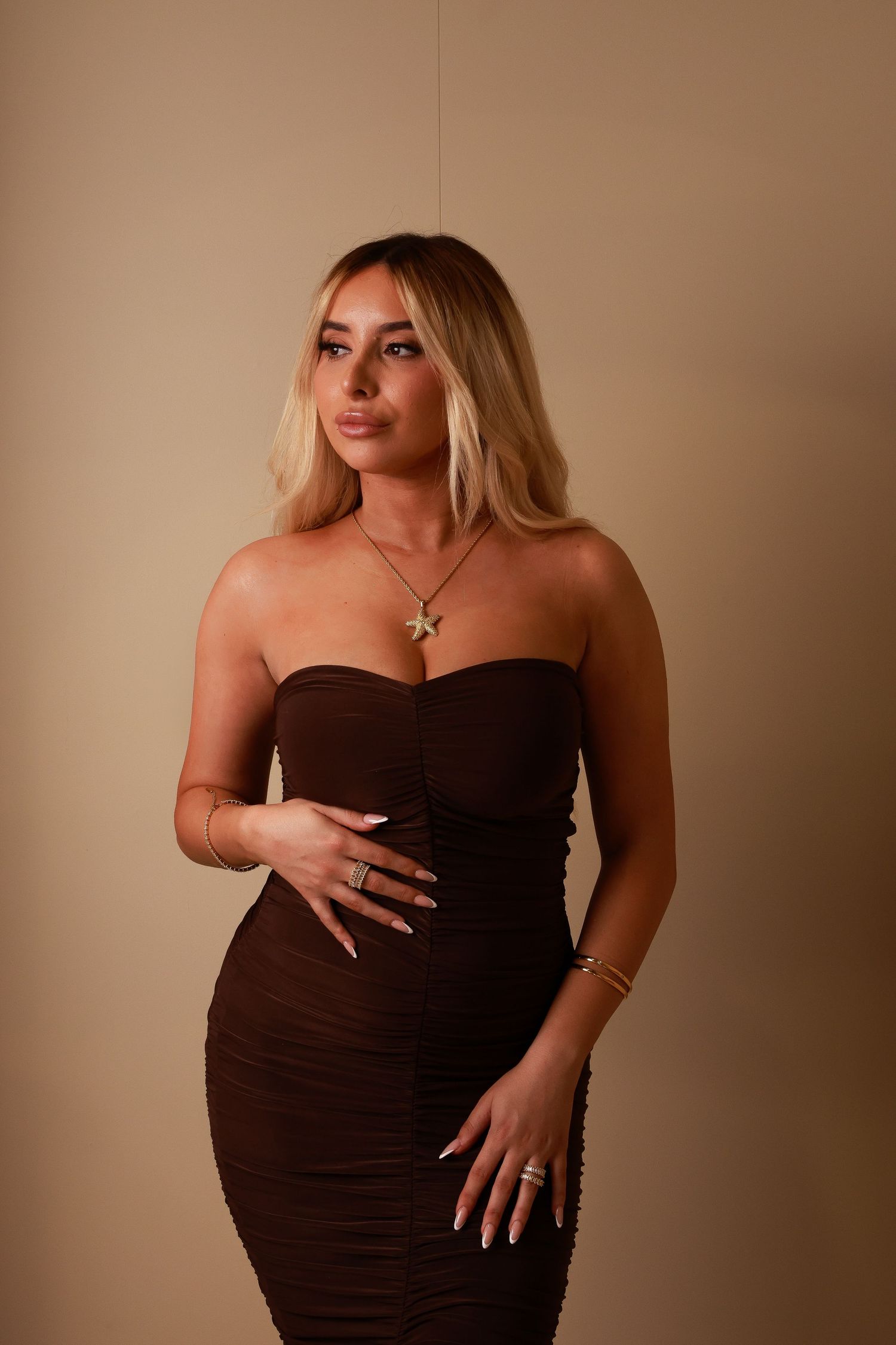 Fashion portrait in brown strapless dress with gold accessories.