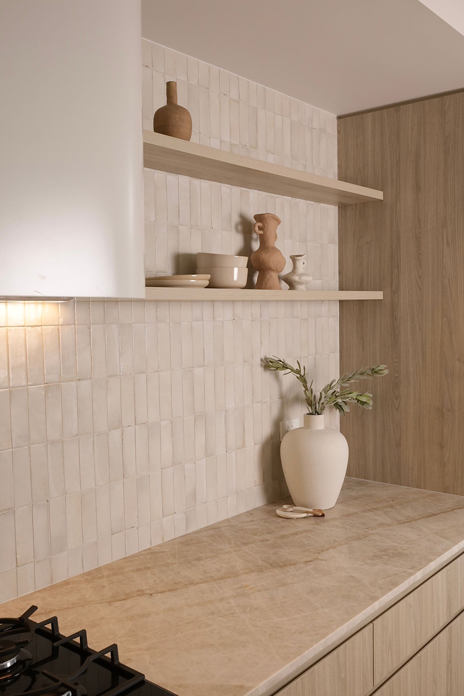 Minimalist kitchen with beige countertops, white tile backsplash, and wooden cabinetry.
