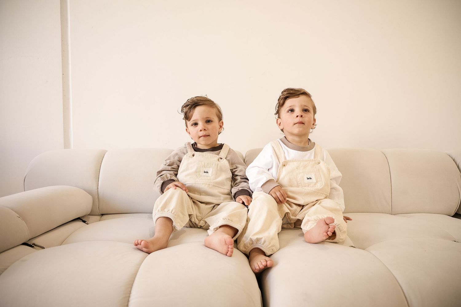 Cozy lifestyle image of cream-colored loungewear on a white sofa.