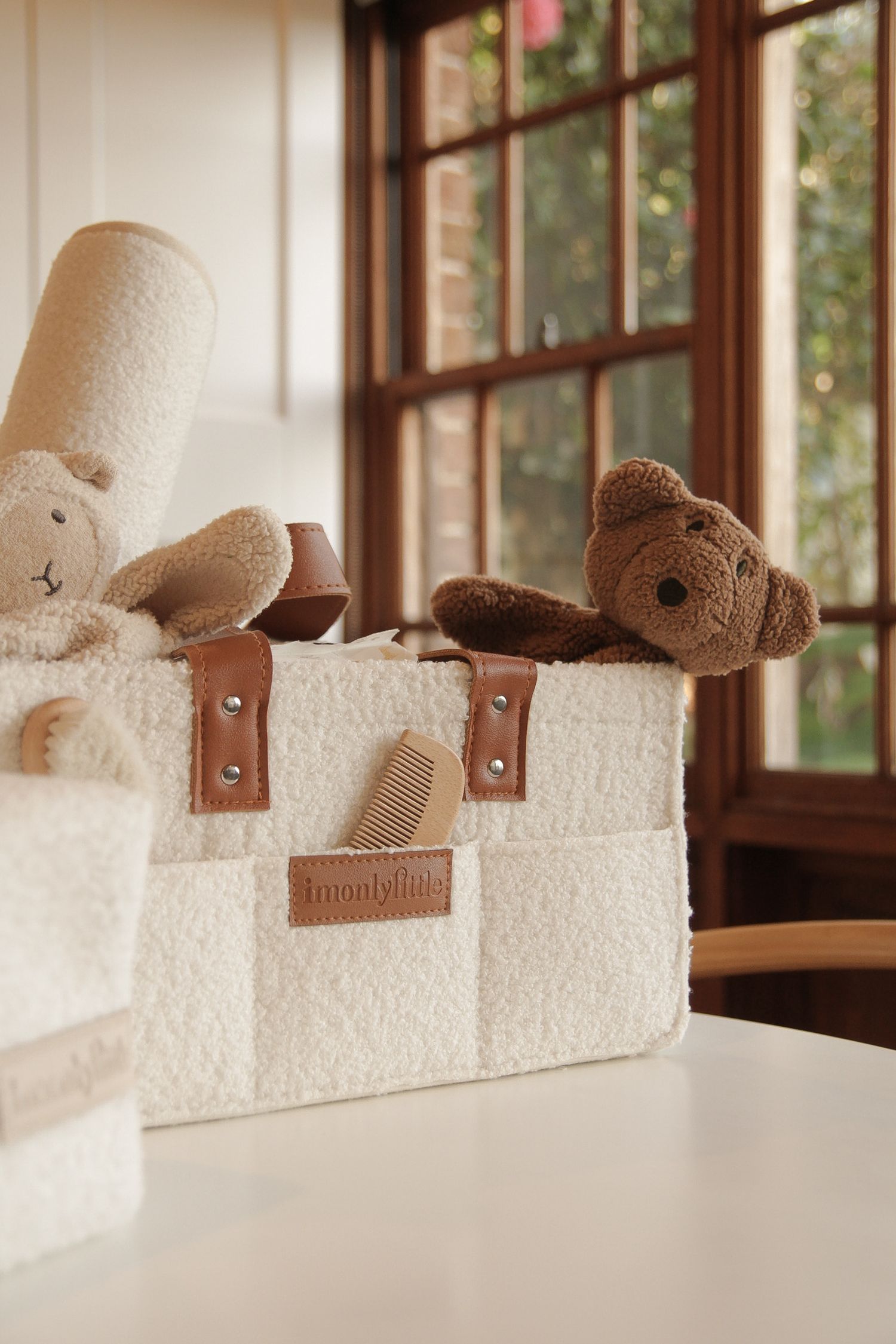 Plush teddy bears peeking out of a cream-colored storage bag with leather handles.