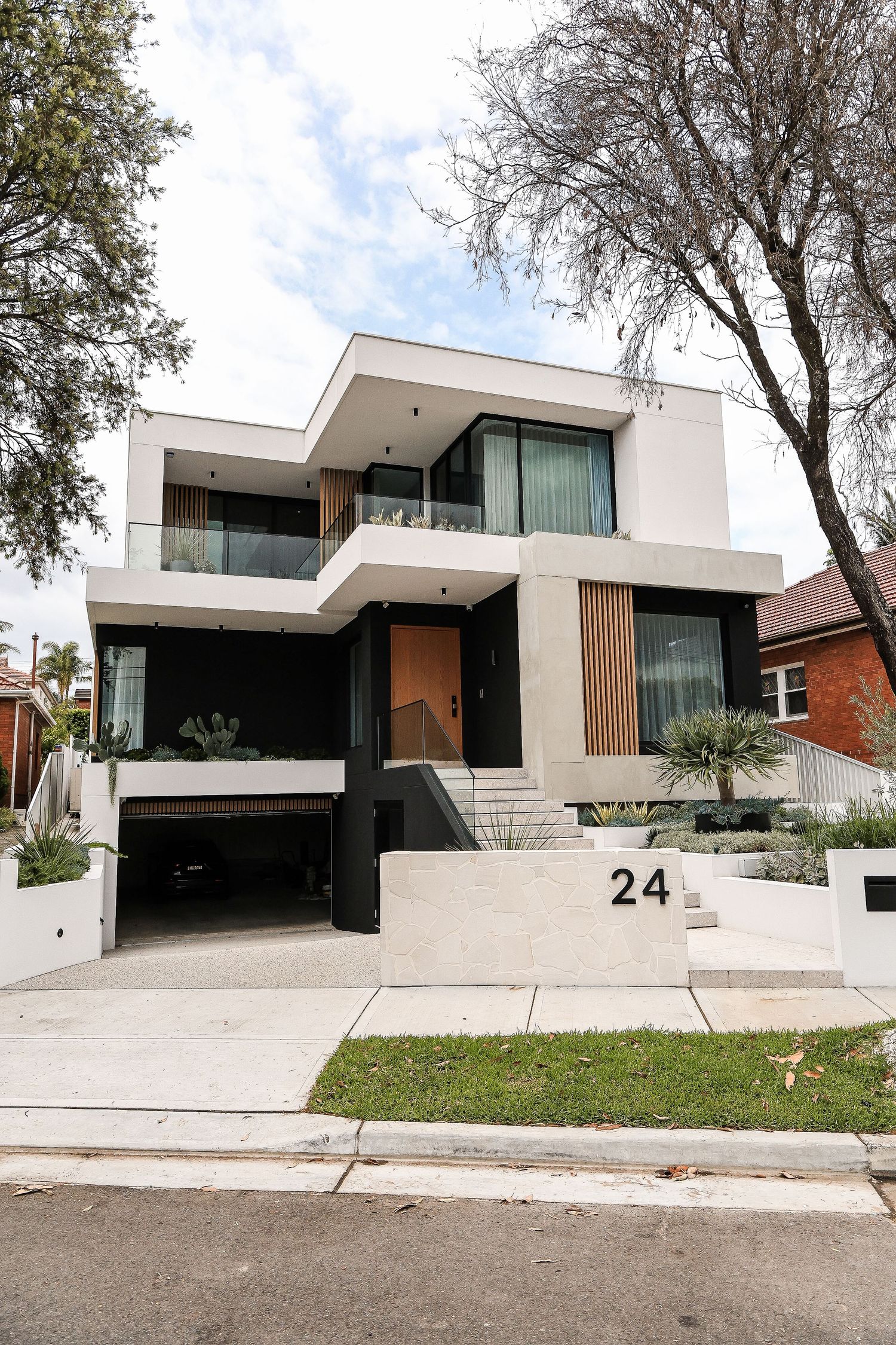 Contemporary white house exterior with angular architecture and wooden accents numbered 24.