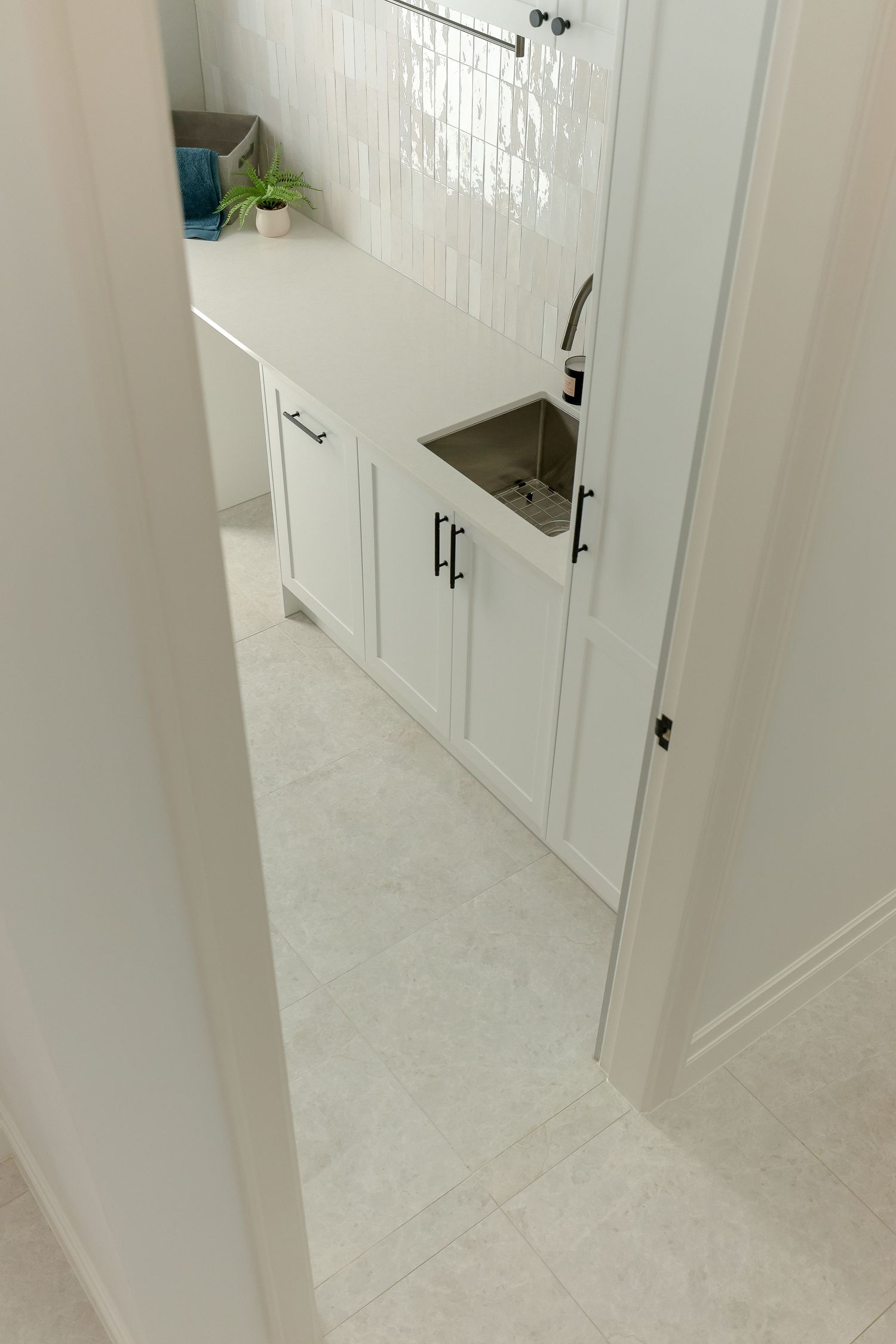 White hallway interior with built-in cabinetry and modern lighting fixtures.