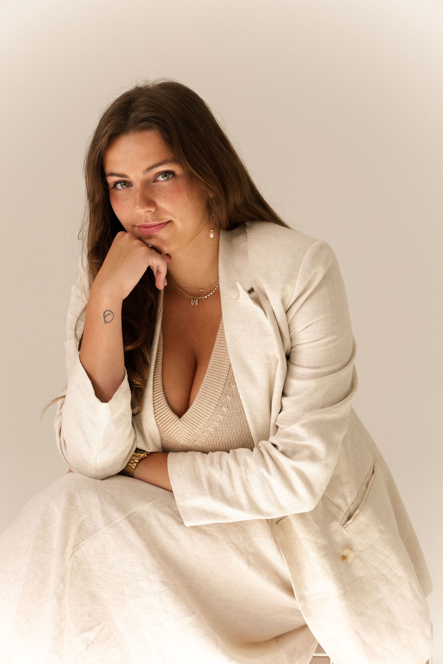 Professional studio portrait of someone in a cream-colored blazer and top against a neutral background.